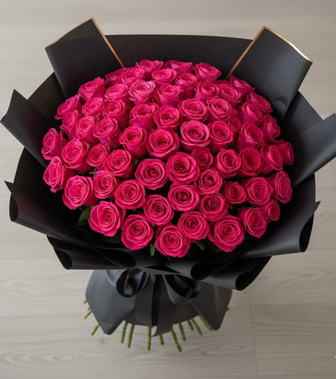 Bouquet of pink roses wrapped in black paper on a light gray background