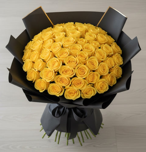 Bouquet of yellow roses wrapped in black paper on a light gray background