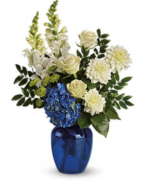 Blue hydrangea and green roses arranged in cobalt vase