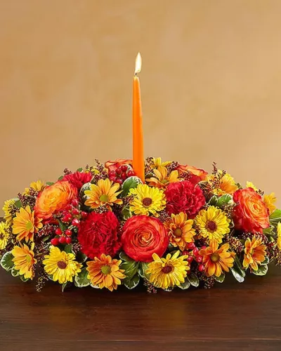 <p>Send your warmest wishes to the people you love with our colorful autumn centerpiece. This traditional table arrangement is designed with radiant blooms and finished off with an orange taper candle to cast a cozy glow over seasonal gatherings.</p>