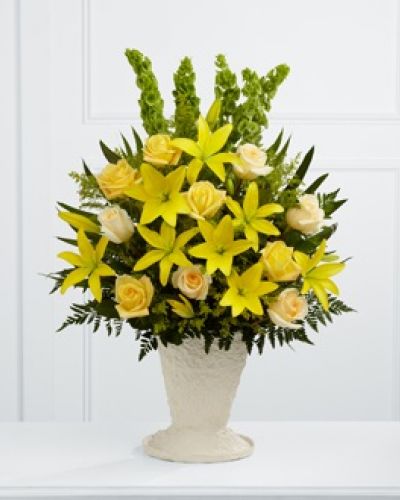 The FTD® Golden Memories™ Arrangement bursts with sunlit beauty to honor the life of the deceased. Brilliant yellow Asiatic lilies, roses and solidago are offset by cream roses, Bells of Ireland, teepee palm fronds and lush greens to create a dazzling display. Arranged in a large papier mache urn, this incredible presentation of floral grace will bring a cheerful elegance to their final farewell service.