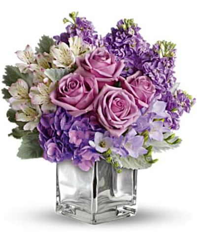 Visions of sugar plum fairies dance to life with this magical bouquet. Lush lavenders, frosty whites and silvery greens look romantic and refreshing inside a cool cube vase.
Robust roses, delicate hydrangea and feminine stock make a cool collection inside an icy, clear glass cube vase.