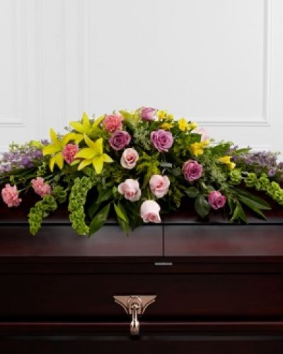 The FTD® Forever Beloved™ Casket Spray beautifully illuminates the atmosphere of their final farewell service. Lavender roses, pink roses, lavender larkspur, pink carnations, Bells of Ireland, yellow Asiatic lilies, yellow freesia, solidago and lush greens are arranged to create an extravagant display of floral beauty that offers comfort and peace to the friends and family of the deceased.