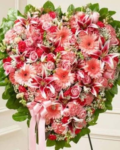 This solid heart standing spray is a beautiful symbol of your sympathy and support. Featuring pink flowers such as roses, stargazer lilies, Gerbera daisies, carnations and more, it is tied to a wire easel with satin ribbon. Traditionally sent directly to the funeral home by family and friends.