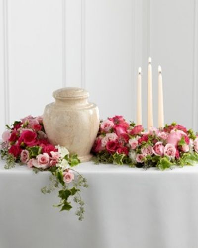 The FTD® Remembrance® Arrangement is a sweetly sophisticated way to display their urn at their final farewell service. Fuchsia and pale pink roses and spray roses are accented with lush greens to form an exquisite arrangement that winds around the base of the urn and curls around 3 ivory taper candles, creating a warm and comforting presentation that commemorates a life that brought kindness and beauty in to the lives of others.