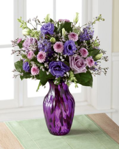 <p>Elegant and chic, this flower bouquet is laced in lavender to send your love, kindness, and gratitude to your recipient this spring season. Lavender roses and purple double lisianthus flaunt their twilight inspired beauty, mingling amongst purple button poms, purple larkspur, pink limonium, and lush greens, presented in a purple swirled glass vase. The perfect thank you, birthday, or Mother's Day gift.</p>