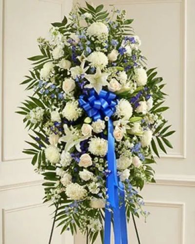 Show the love and compassion you have in your heart during times of loss with our beautiful blue and white standing spray. This expertly crafted standing spray arrangement is a tasteful and touching expression of your care and concern featuring fresh blue delphinium gathered with white roses, lilies, mums, stock, carnations and more. Appropriate for family, friends or business associates to send directly to the funeral home.