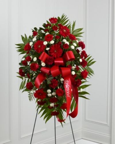 <p>The FTD® Treasured Memories™ Standing Spray is a rich and colorful way to express your unending love and devotion to the departed. An exceptional arrangement of red roses, burgundy carnations, burgundy mini carnations, red gerbera daisies and white button poms are accented with a variety of lush greens. A red ribbon with the word, "Beloved," embossed in a gold metallic lettering, finishes this beautiful display for their final farewell service. Displayed on a wire easel.</p>