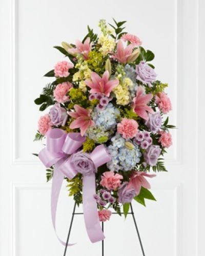 The FTD® Blessings of the Earth™ Easel is a soft and serene arrangement that elegantly honors the life of the deceased. Lavender roses, pink carnations, pink Asiatic lilies, blue hydrangea, yellow stock, lavender button poms, solidago and lush greens are beautifully accented with a lavender satin ribbon and displayed on a wire easel to create a gorgeous display for their memorial service.