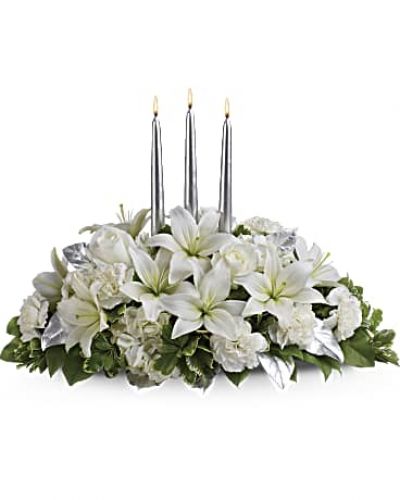 Blanket your holiday table in elegance with this lush white floral Christmas centerpiece. Beautiful white hydrangeas and lilies form a snow white cloud beneath three slender silver candles.
White flowers, including hydrangeas, asiatic lilies and carnations - are combined with deep green salal, variegated pittosporum and silver leaves beneath three silver taper candles.