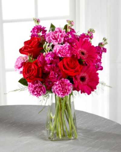 <p>The power of pink is packed into one beautifully blushing bouquet to make your recipient's day one they will never forget! Red roses make the hot pink petals of carnations, fuchsia double bloom stock, and gerbera daisies pop in this fun and fanciful flower arrangement accented with lush greens and presented in a gathered square clear glass vase.</p>