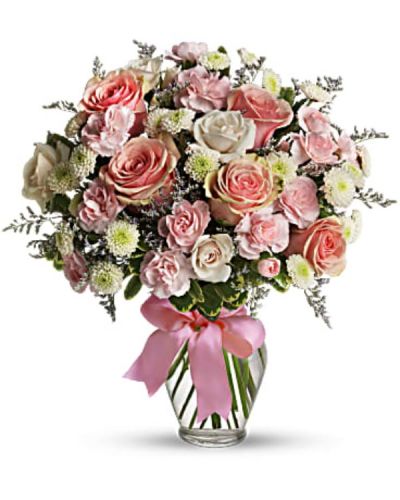 <p>Pretty pink roses, spray roses and miniature carnations, white button spray chrysanthemums, lavender limonium and green pittosporum fill a spring glass vase that's wrapped with a pink satin ribbon. It's confection perfection!</p>