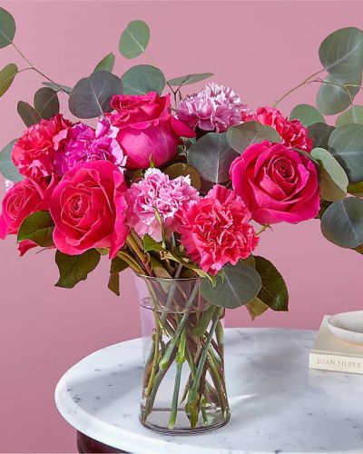 <p>Who knew hugs and kisses could grow on trees? Blooming with jewel–toned carnations and hot pink roses surrounded by adorable eucalyptus stems, this florist-crafted arrangement will make them feel extra loved.</p>